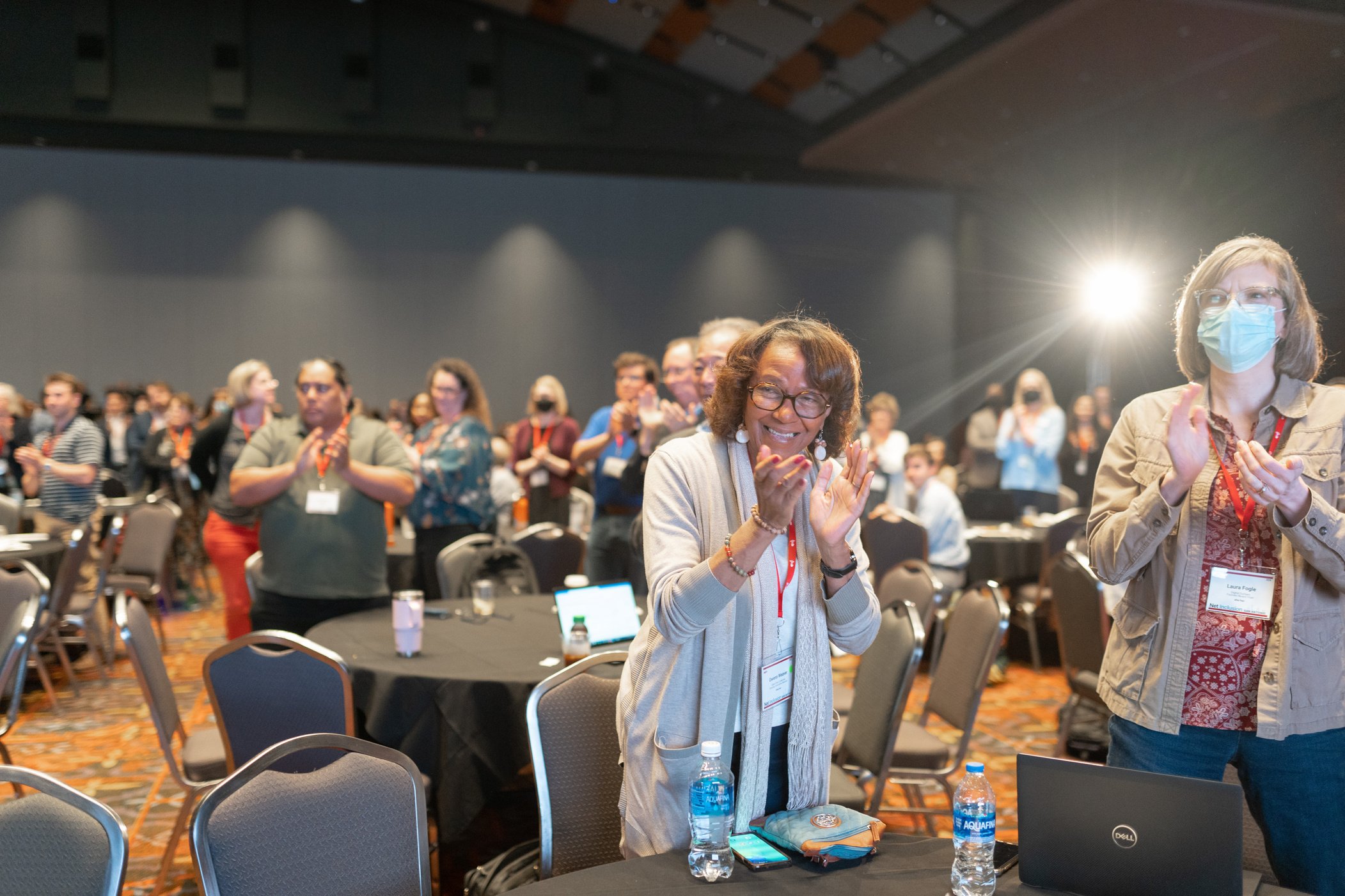 a group of people standing and clapping in a conference room
